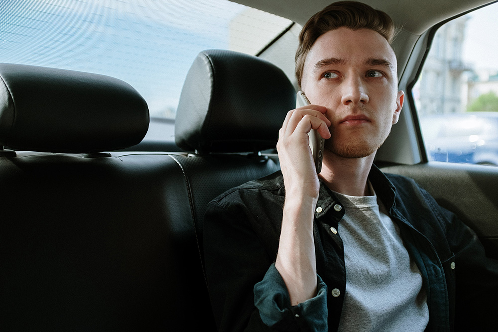 Ein junger Mann telefoniert mit der Hotline des Unfallopfer-Hilfswerkes auf der Rückbank eines Autos
