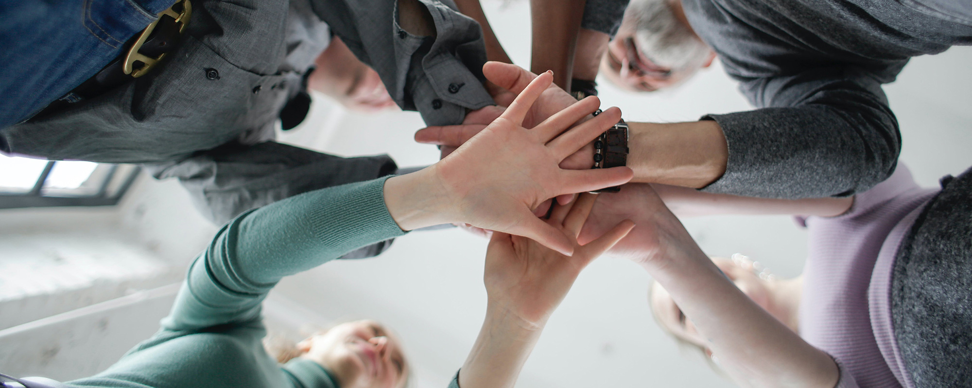 Ein starkes Team für Unfallopfer: Aus der Froschperspektive sind mehrere Menschen zu sehen, die ihre Hände in der Mitte aufeinanderlegen – ein Symbol für Zusammenhalt, Unterstützung und Engagement. Das Team des Unfallopfer-Hilfswerks setzt sich mit Leidenschaft für die Unterstützung von Unfallopfern ein. Mit ihrer Erfahrung und Empathie helfen sie Betroffenen dabei, nach einem Unfall wieder Fuß zu fassen. Gemeinsam stehen sie für Inklusion, Gerechtigkeit und Teilhabe und zeigen, dass niemand mit seinen Herausforderungen allein ist. Ihre Aufgabe ist es, Wege aufzuzeigen und Unfallgeschädigten zu helfen, ihr Leben wieder selbstbestimmt zu gestalten.
